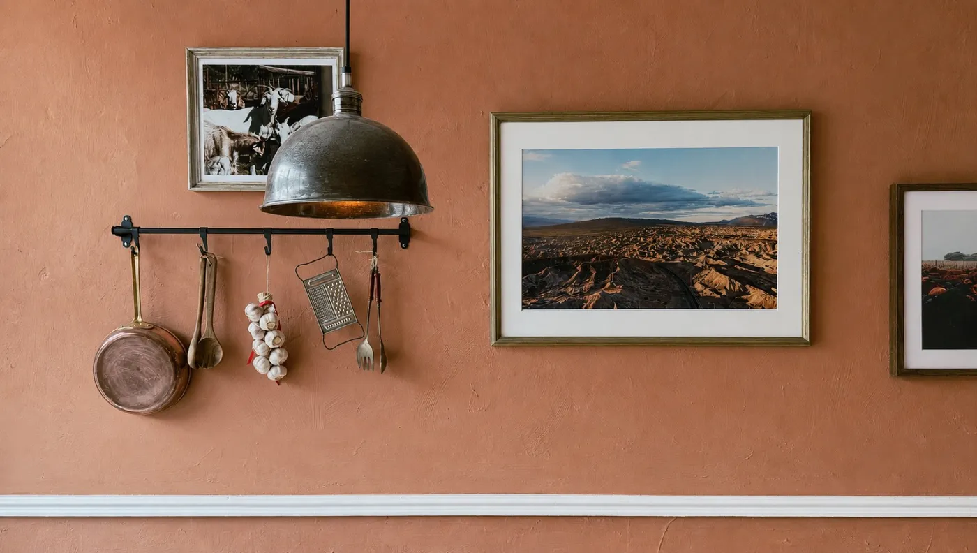 Copper pots and framed prints on the warm terracotta wall of the café