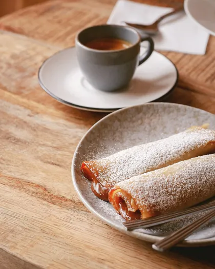Sugar-dusted pastries beside an espresso